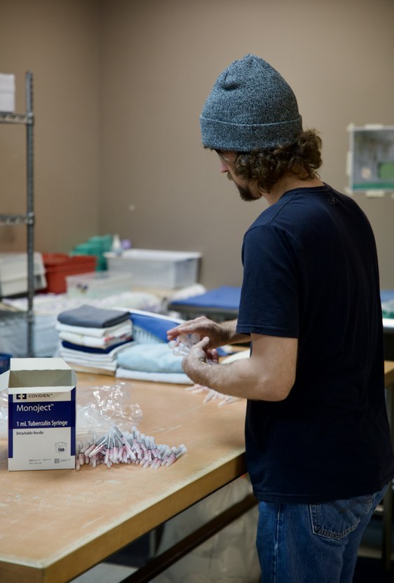Erik preparing and organizing syringes and supplies at a prep table