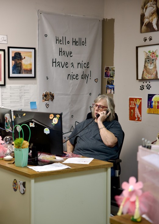 Shellee answering the phone at the front desk beneath a hand-lettered 'Have a nice day' banner